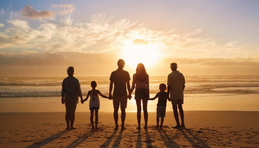 Familie op het strand met ondergaande zon